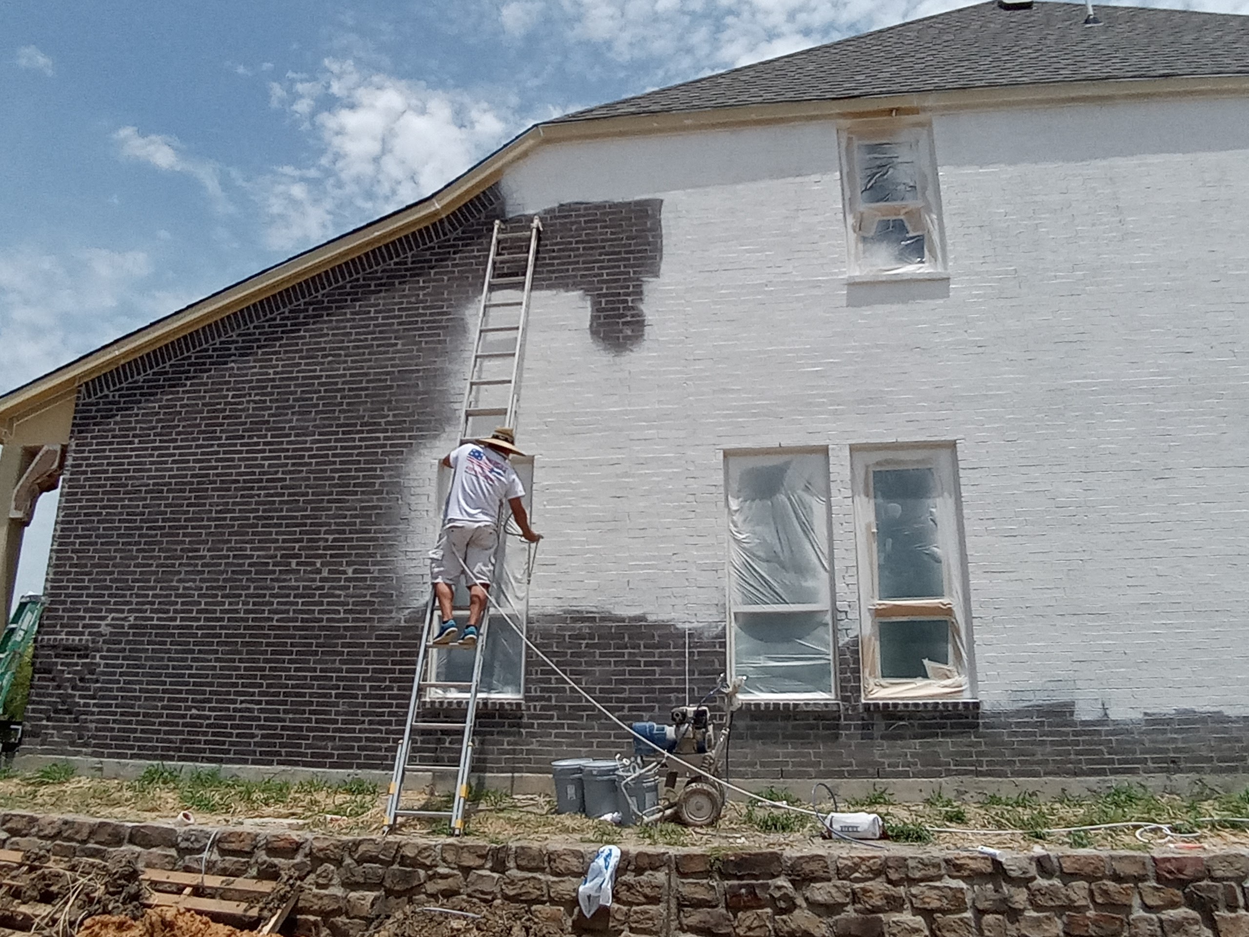 a man painting the outside of a building white