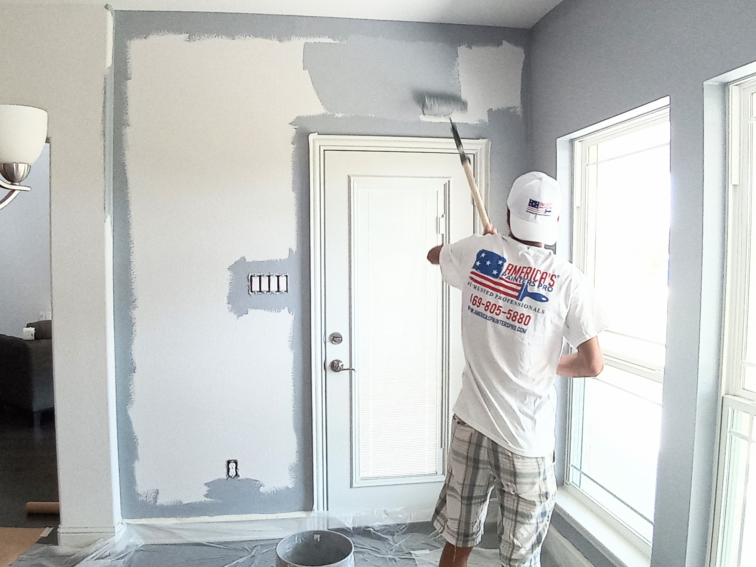 A man painting a house wall white