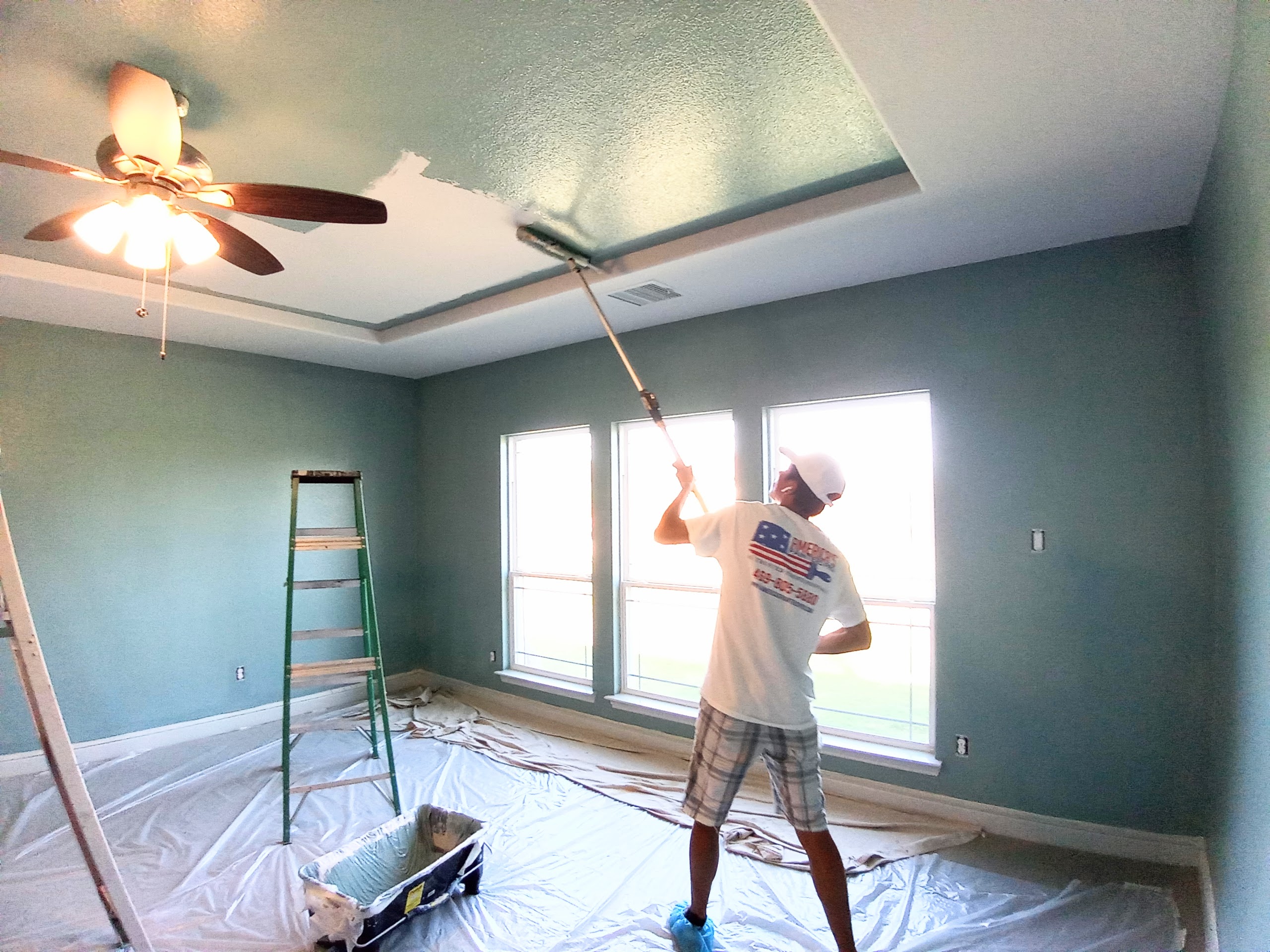 a man painting the ceiling of a house blue