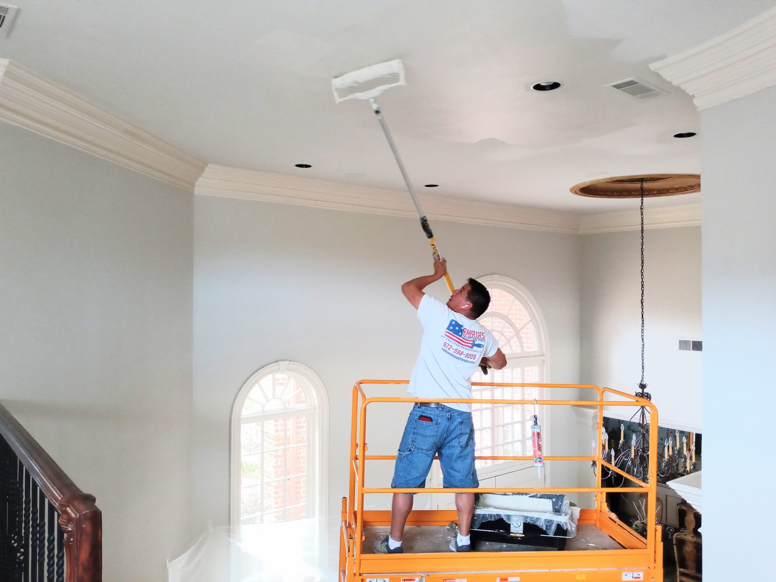 A man painting the ceiling of a house